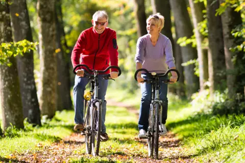 Ein älteres Paar fährt Fahrrad durch den Wald