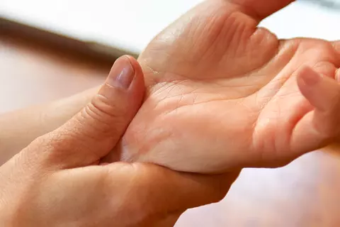 Frau fasst sich an die Handgelenke