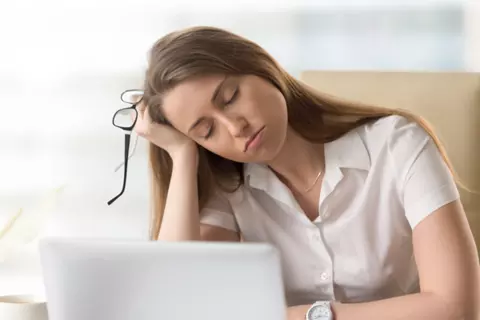 Frau ist müde und schläft am Laptop ein