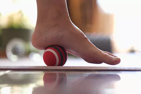 Ferse wird vorsichtig über einen kleinen Ball gerollt