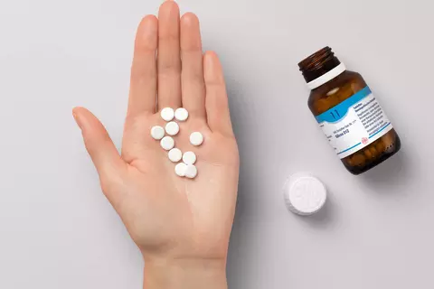 Tabletten des DHU Schüßler-Salz Nr. 11 liegen auf einer Hand.