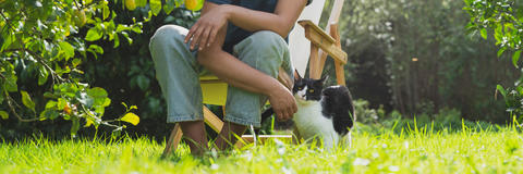 Frau sitzt mit einer Katze im Garten