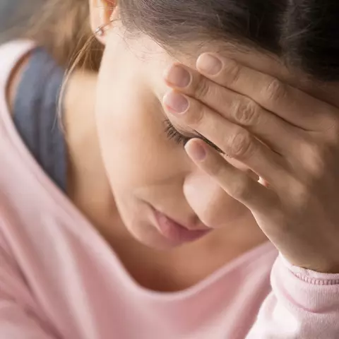 Frau ist schwindlich und hält sich den Kopf