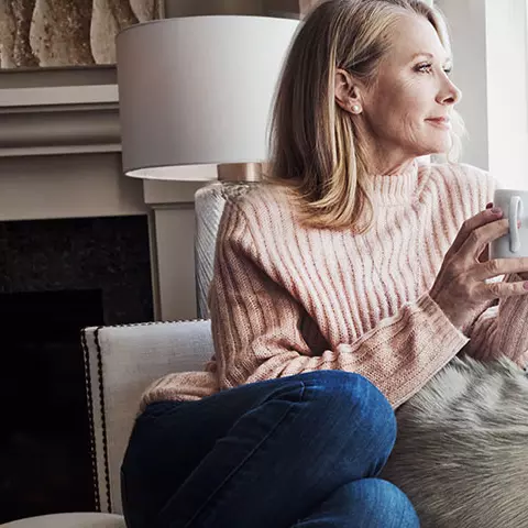 Frau sitz mit einer Tasse am Fenster