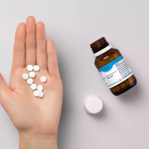 Tabletten des DHU Schüßler-Salz Nr. 11 liegen auf einer Hand.