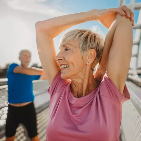 Senior und Seniorin machen draußen Sport